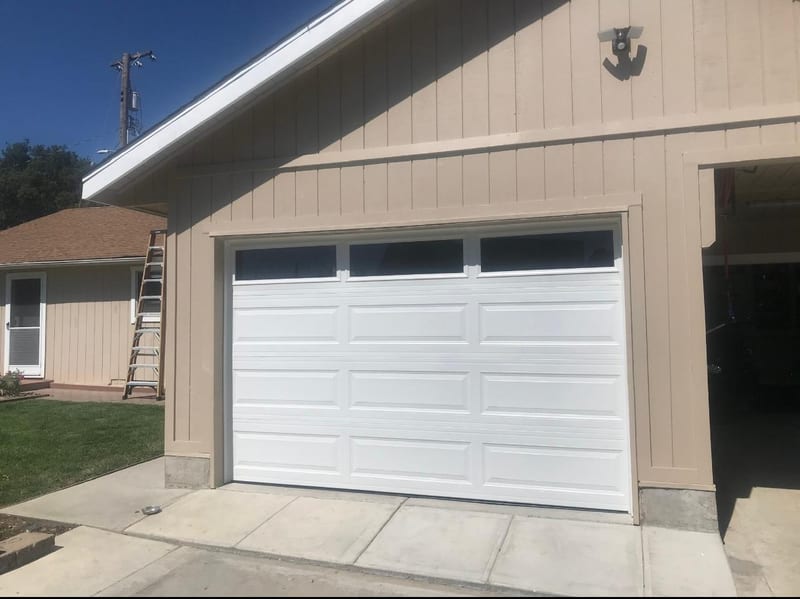 New white sectional garage door with a window row after a replacement