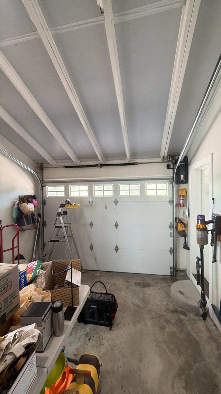 Inside a one-car garage: torsion spring above the door and a wall-mounted opener beside it